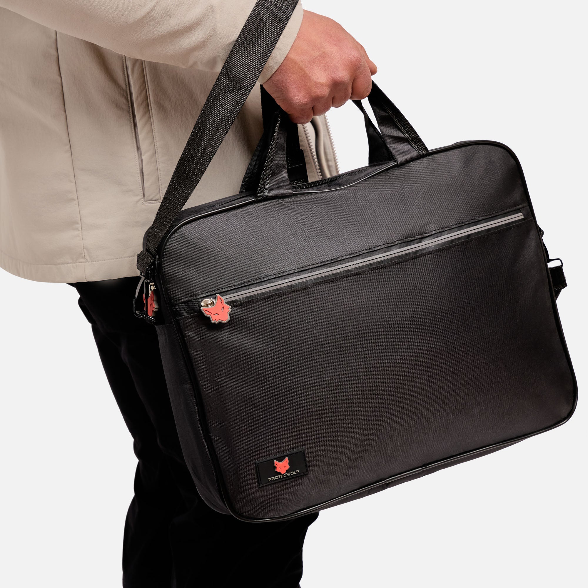 Person holding a black laptop bag with a visible brand logo on a light gray background