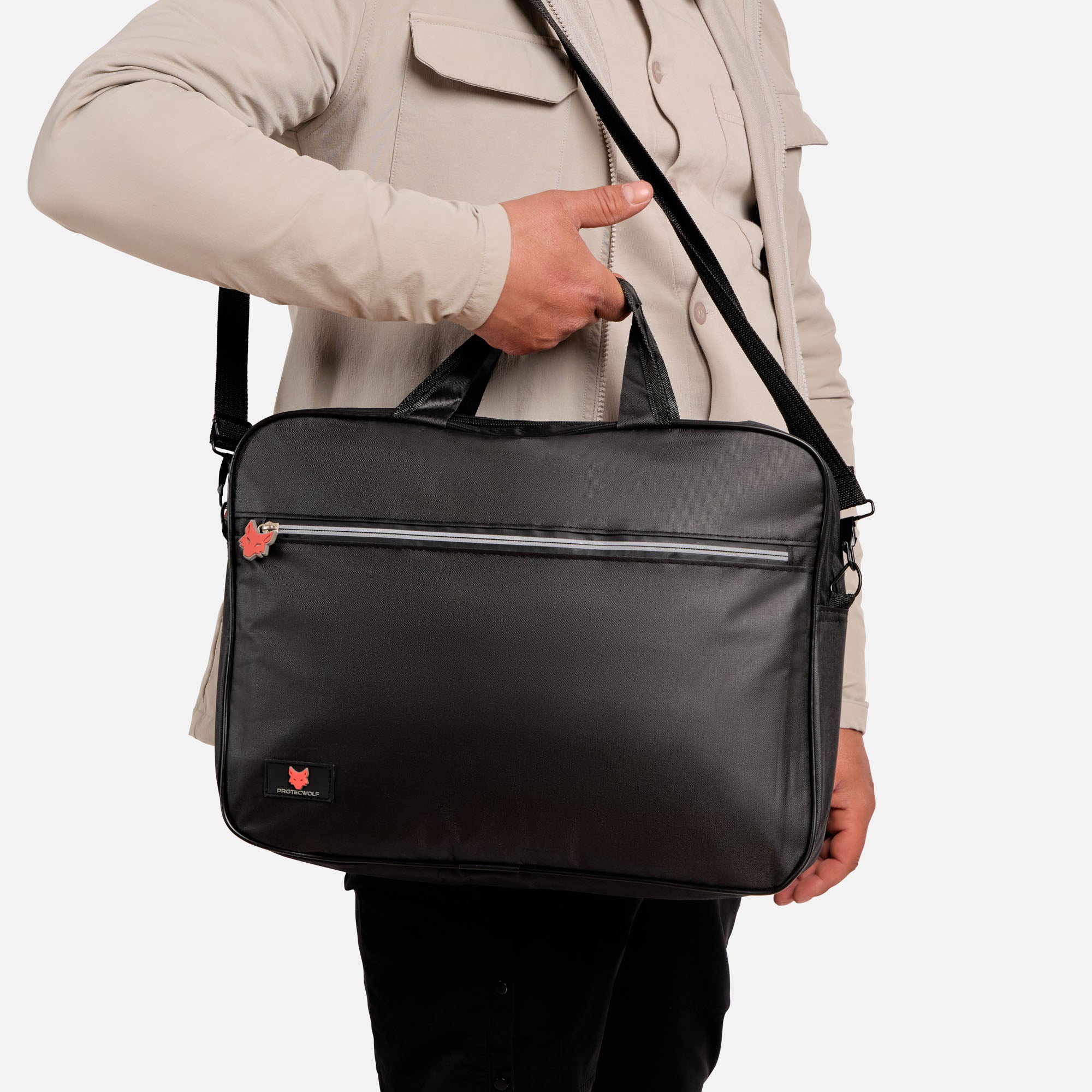 Person holding a black shoulder bag with a visible brand logo on a light gray background